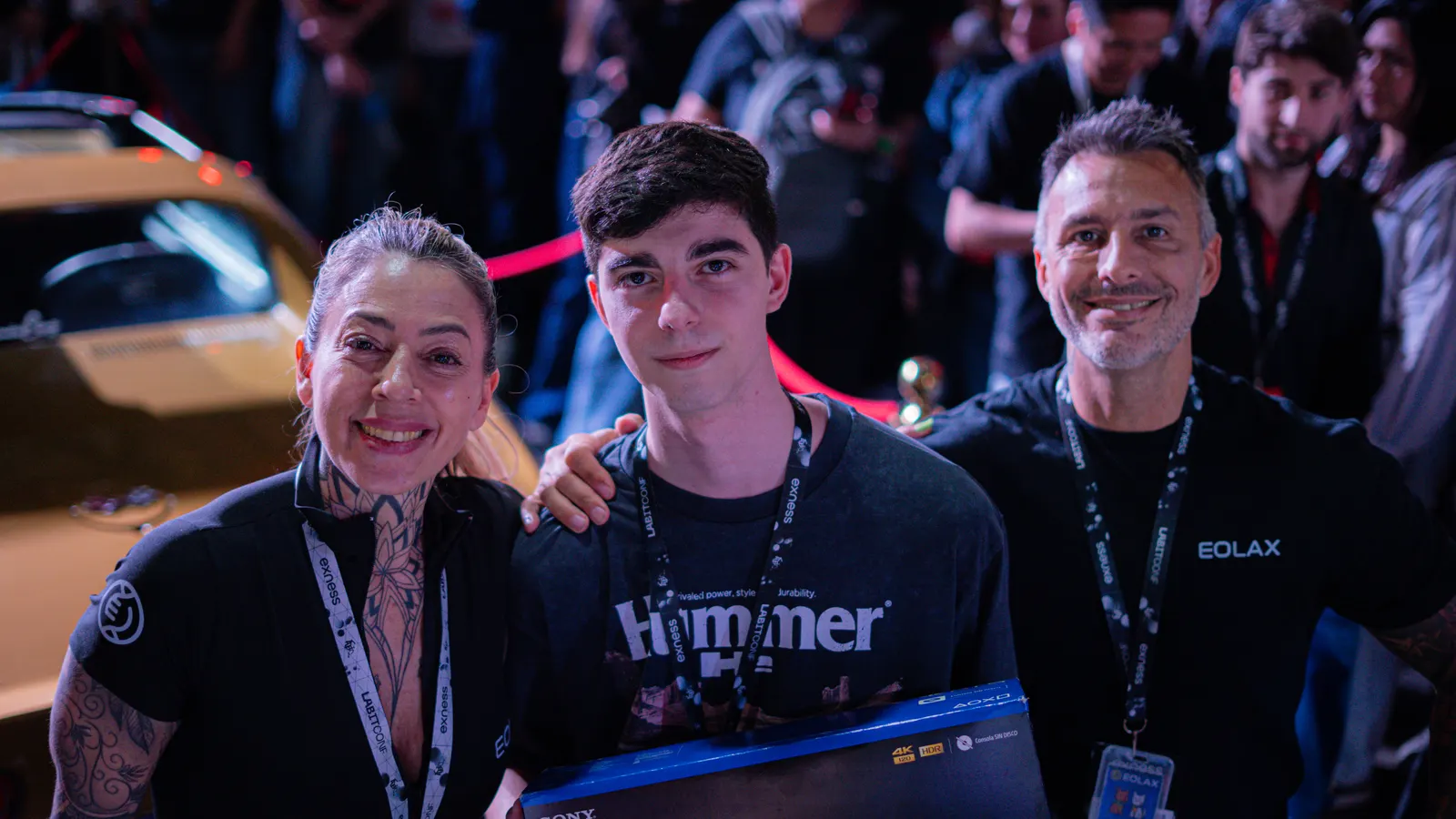 The PlayStation 5 winner holds his box between two members of the Eolax team, the Corvette behind them.