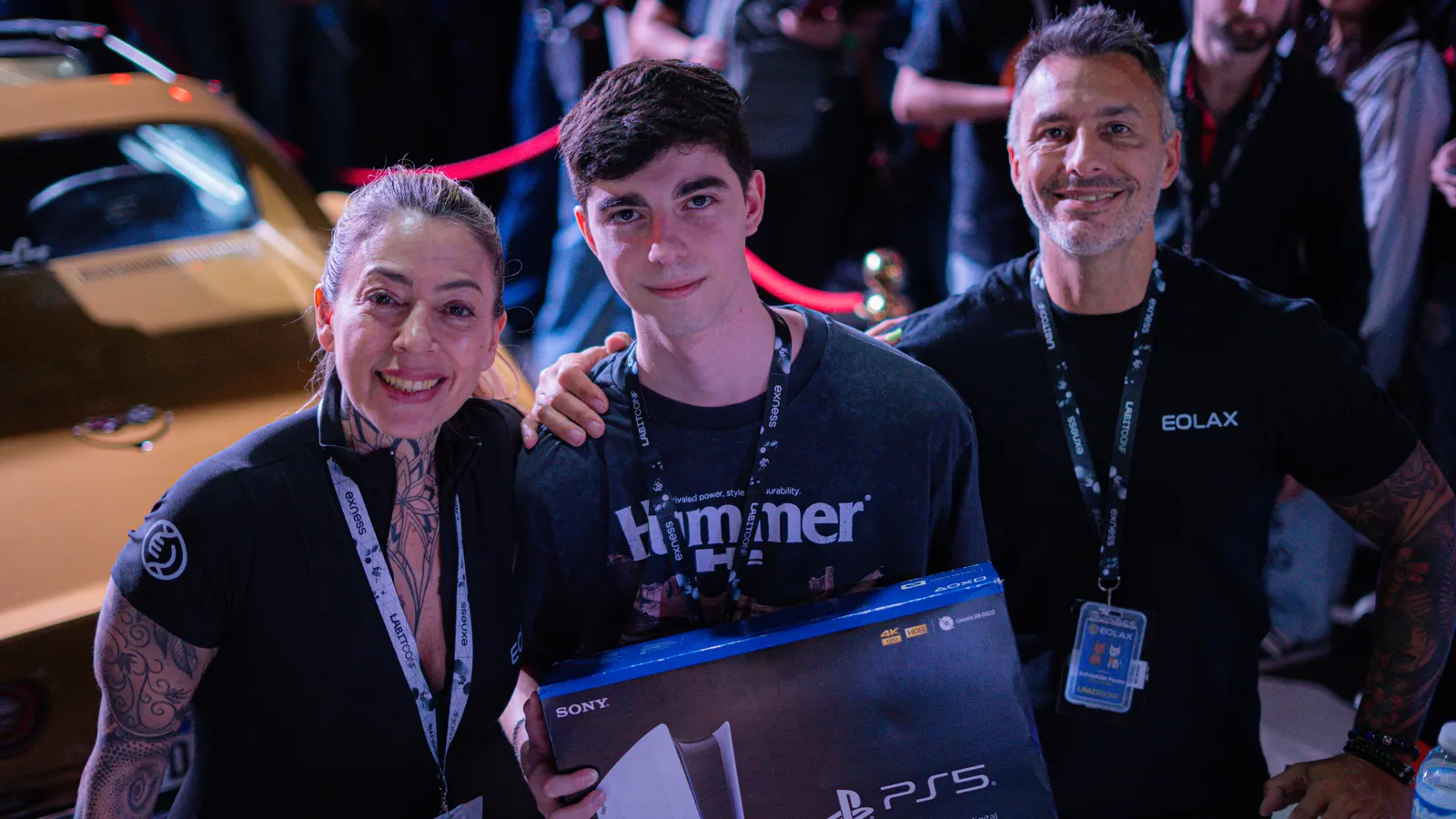 The same group on the stand, smiling with the console box held up.
