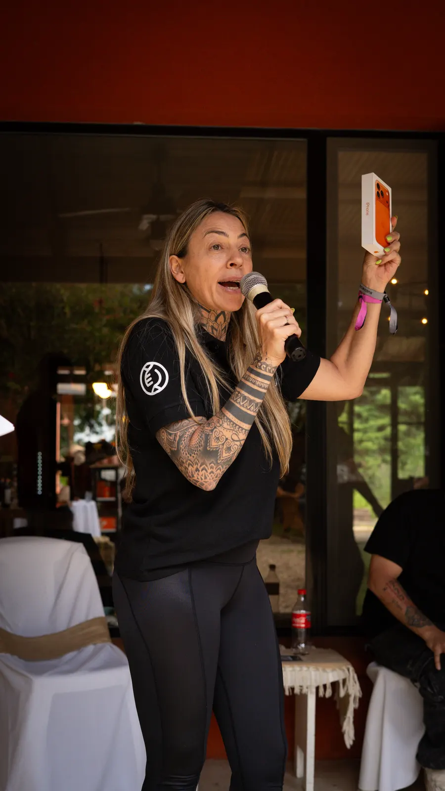 The Eolax host speaks into a microphone in front of the guests, holding up what she is announcing.