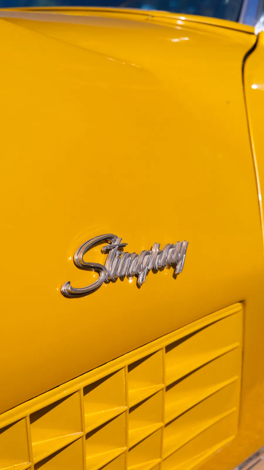 The chrome Stingray emblem on the Corvette's gold bodywork.