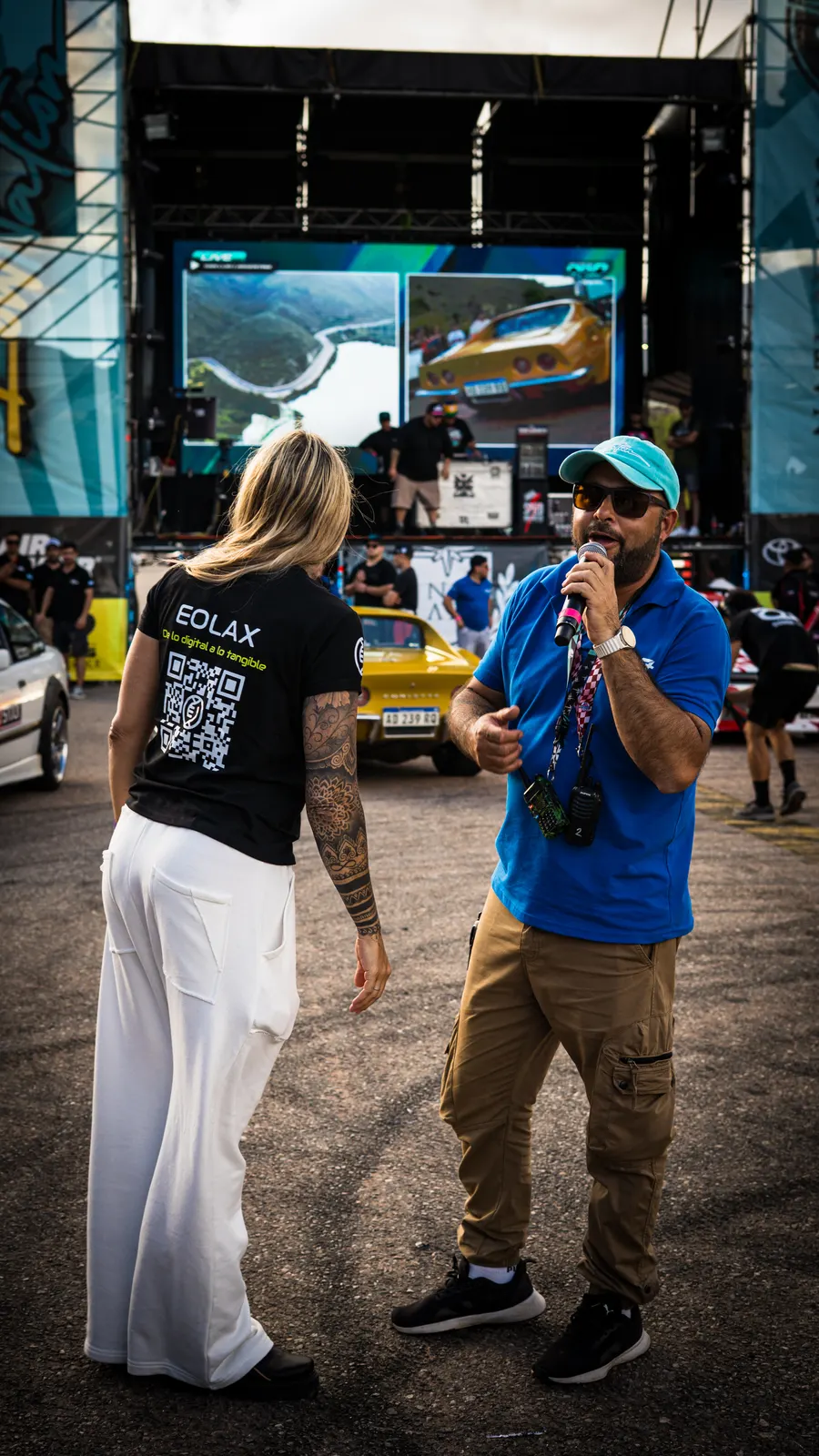 The Eolax host, the QR code on the back of her shirt, speaks alongside the event announcer on the track.