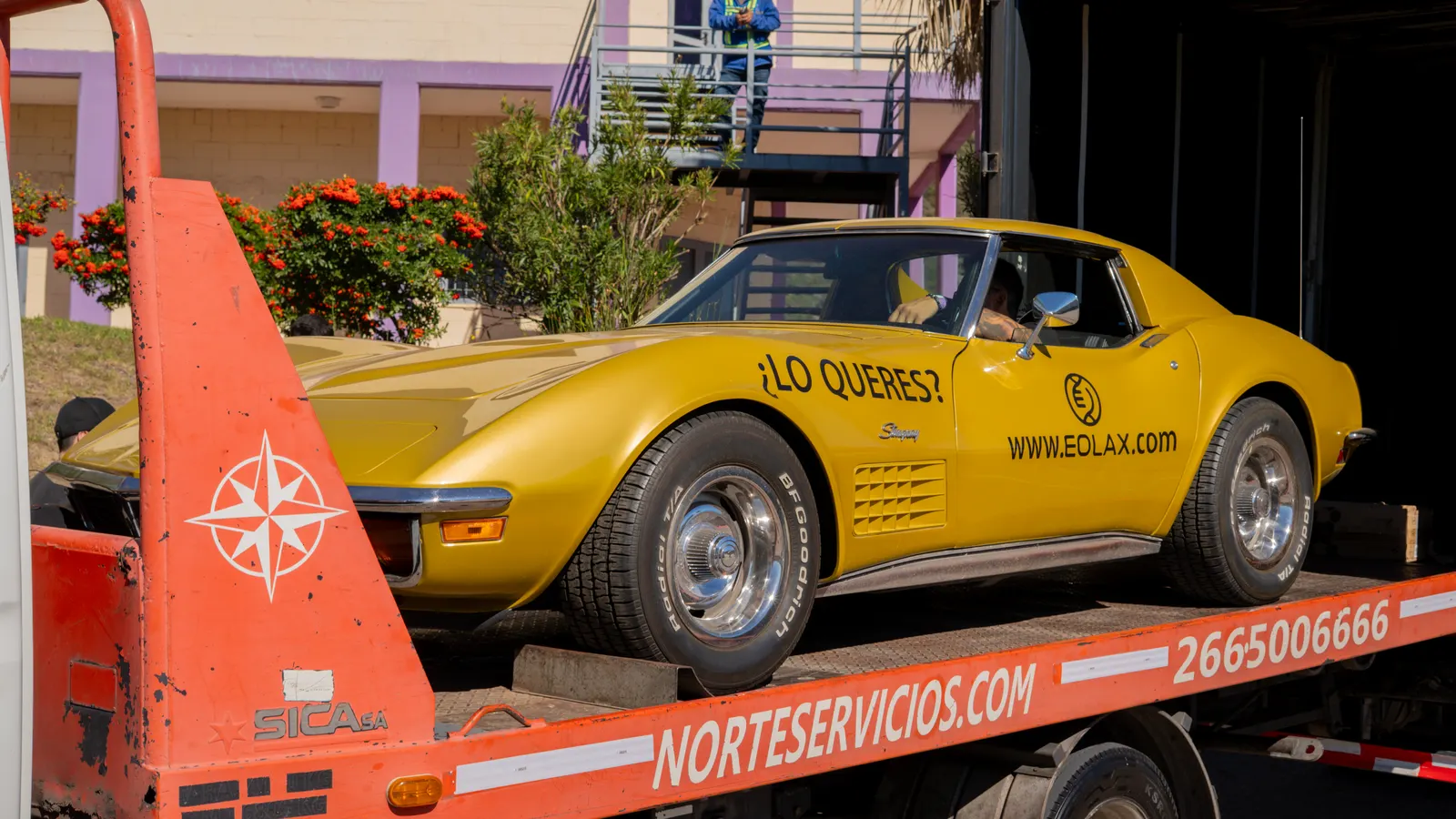 The Corvette arriving in San Luis on a flatbed tow truck, the hills and the circuit behind it.