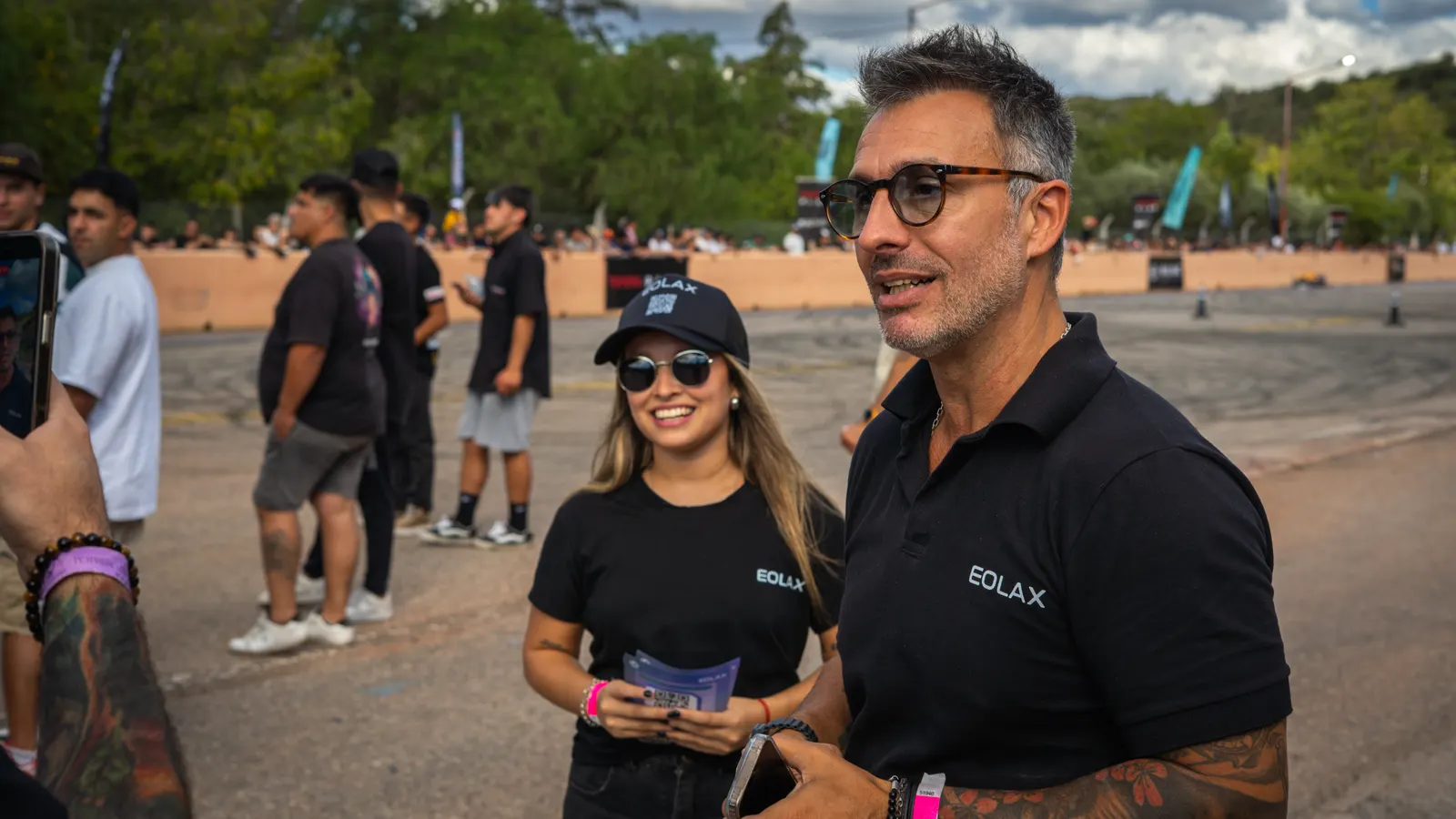 Two Eolax team members talk with a guest holding her ticket in the paddock.