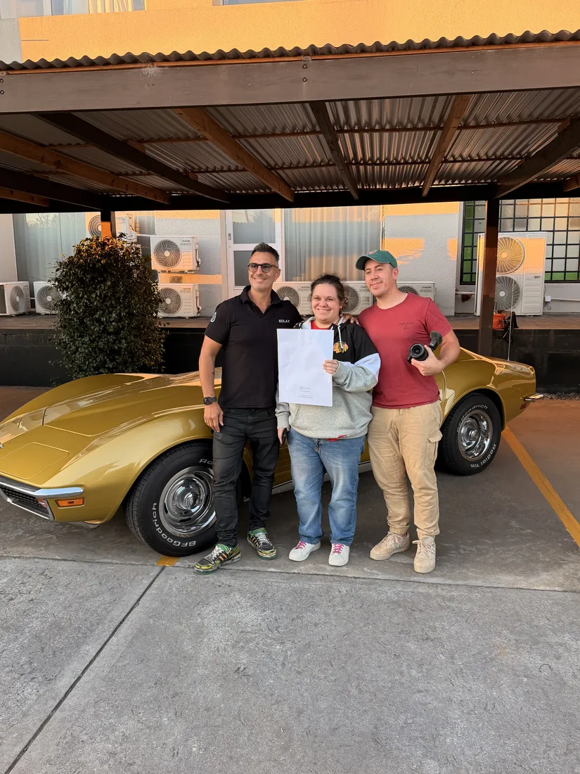 Laura P. junto al equipo de Eolax con el certificado, delante del Corvette.